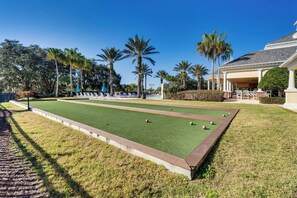 Un campo de croquet con césped, palmeras y un edificio con columnas.