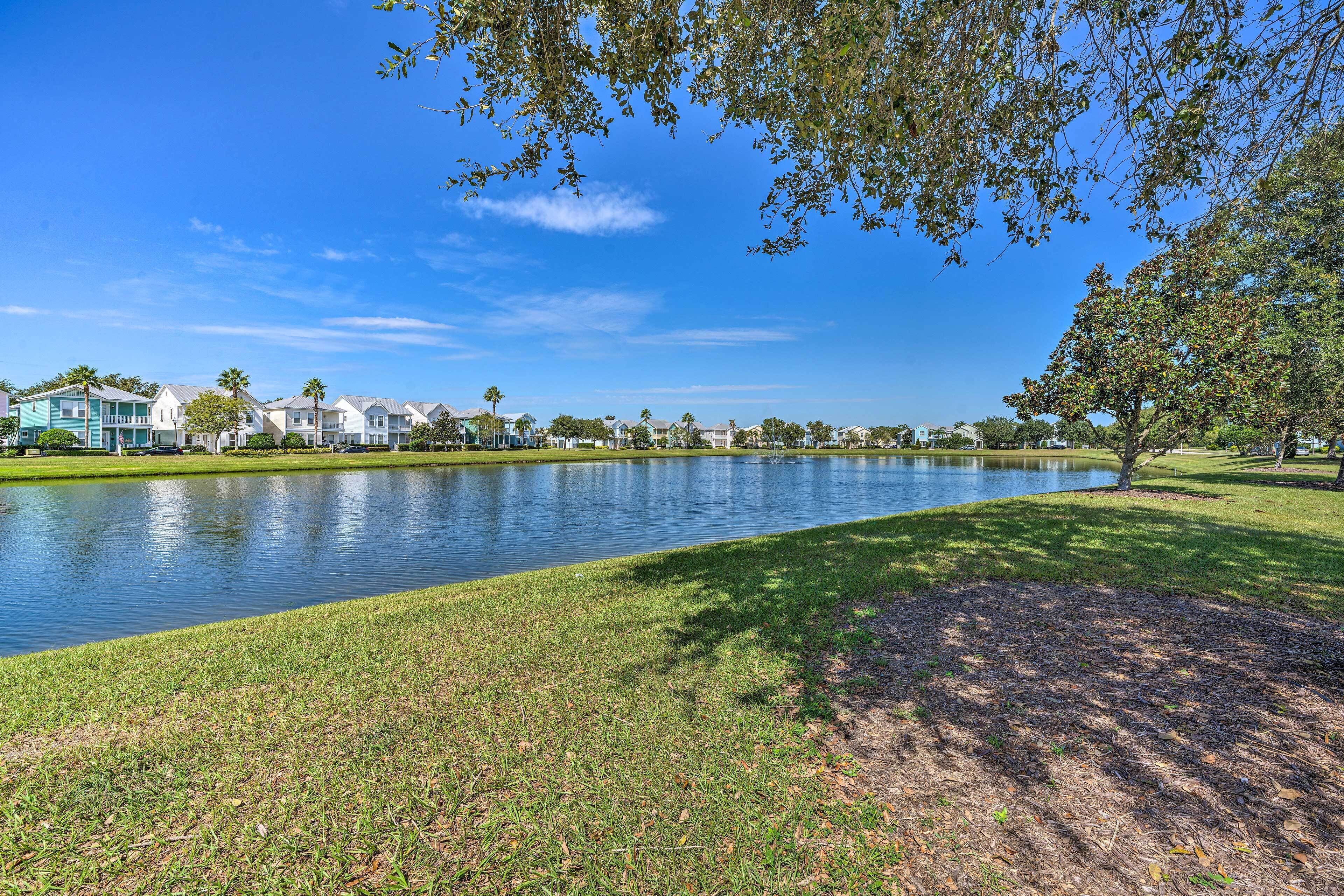 Une vue sur le lac, avec une rangée de maisons, une zone herbeuse et un ciel dégagé.