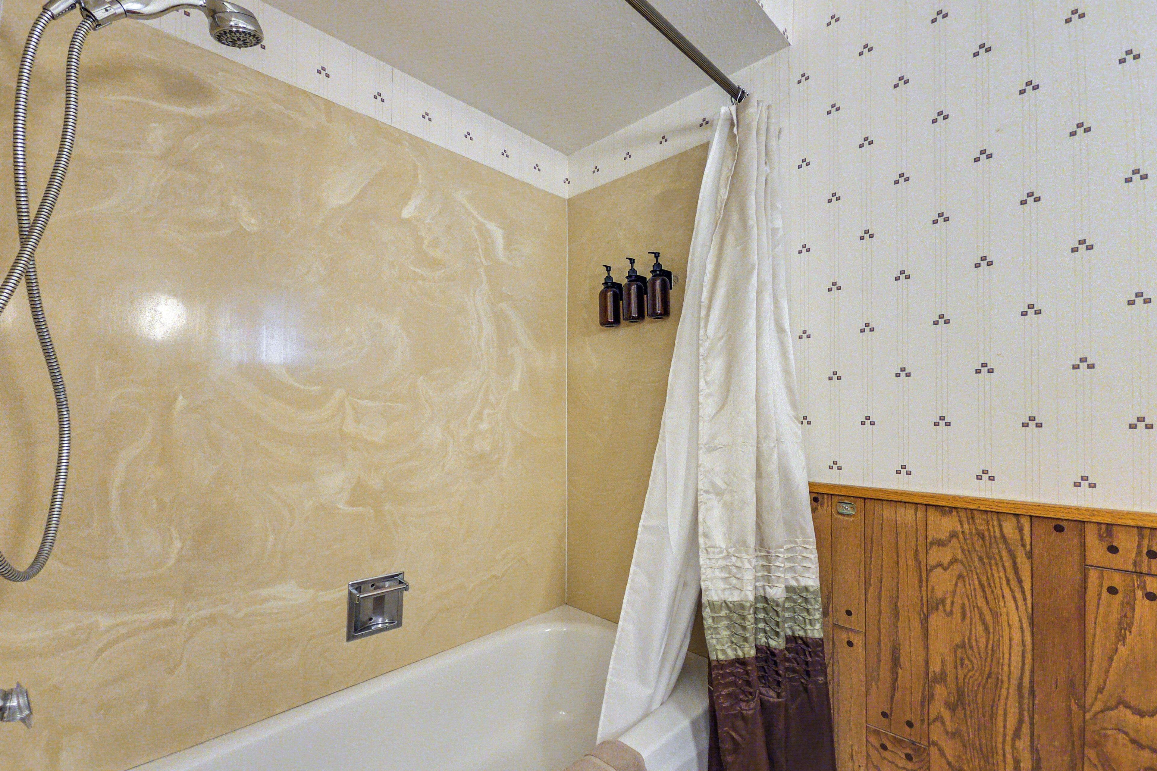 Een badkamer met een bad, douche en een wand van hout.