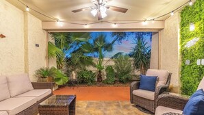 A cozy patio area with wicker furniture, a ceiling fan, and a view of a garden. - Walk to Old Town & Fashion Square, Condo w/ Patio! (Scottsdale)
