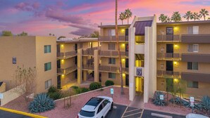 A multi-story hotel with balconies, a parking area, and a sunset sky. - Walk to Old Town & Fashion Square, Condo w/ Patio! (Scottsdale)