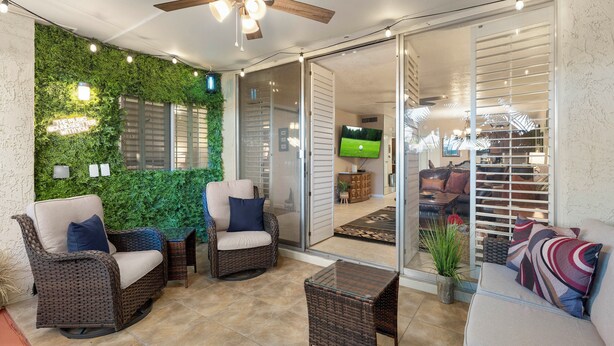 A patio area with wicker furniture, a ceiling fan, and a green wall. - Walk to Old Town & Fashion Square, Condo w/ Patio! (Scottsdale)