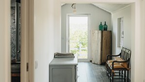 Ein Korridor mit Holzboden, einer Bank, einem Schrank und einer Tür, die auf einen Balkon führt.