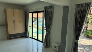 Een ruime kamer met een grote inbouwkast, een schuifdeur van glas naar een buitenruimte en een ingebouwde airconditioning.