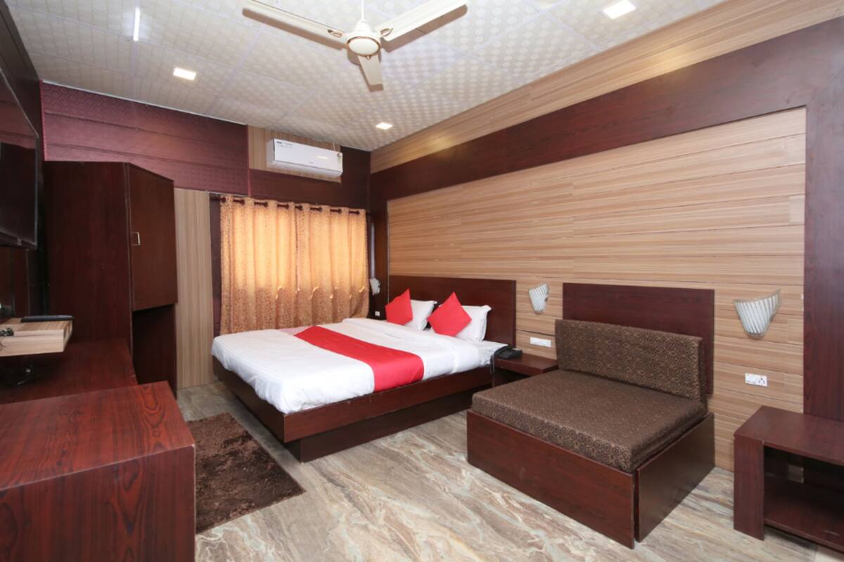 A modern bedroom with a large bed, a sofa bed, a desk, and a wardrobe.