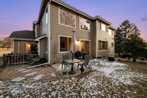 A two-story house with a patio area featuring a table and chairs, a wooden fence, and a large tree. - New Listing! Pinery Lakeshore Retreat | Near Park (Parker)