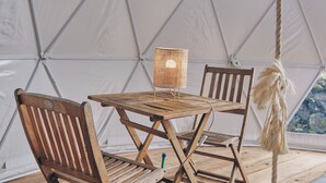 A tent with a wooden table and two chairs, a hanging rope, and a window with a view. - Quinta do Abacate (Angra do Heroismo)