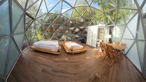 A glass-domed room with two beds, a wooden table, and a chair. - Quinta do Abacate (Angra do Heroismo)