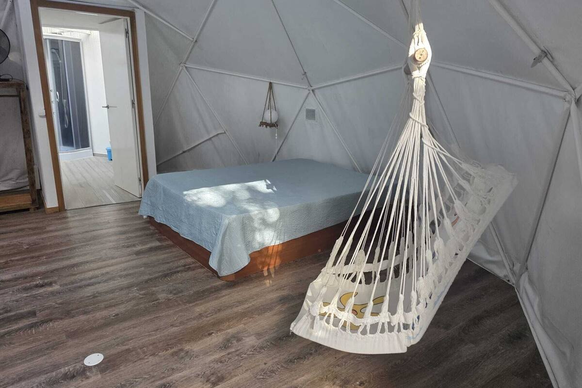 Una carpa con una cama y una hamaca colgada.