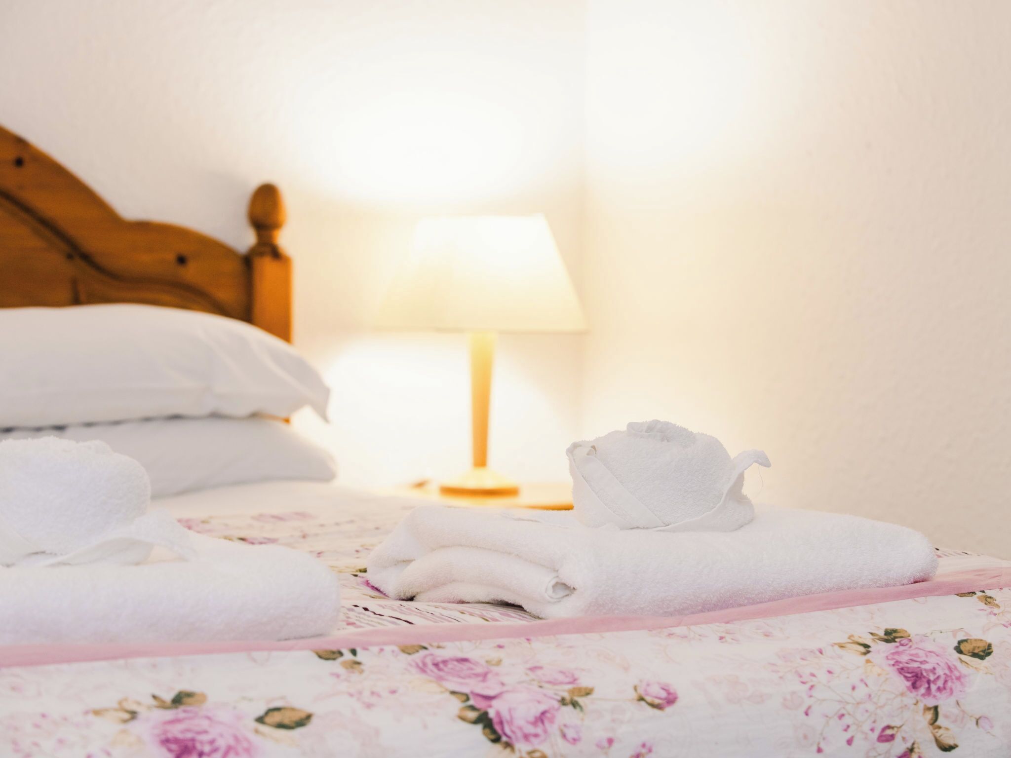 A neatly made bed with white towels and a floral-patterned bedspread.