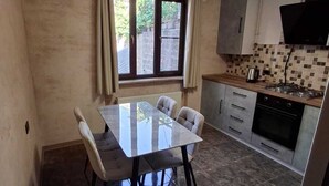 A modern kitchen with a dining table and chairs, a tiled backsplash, and a built-in oven.