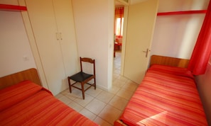 A room with two single beds, a wooden chair, and a wardrobe. - Cozy Villa Close to the Beach (Lignano Sabbiadoro)