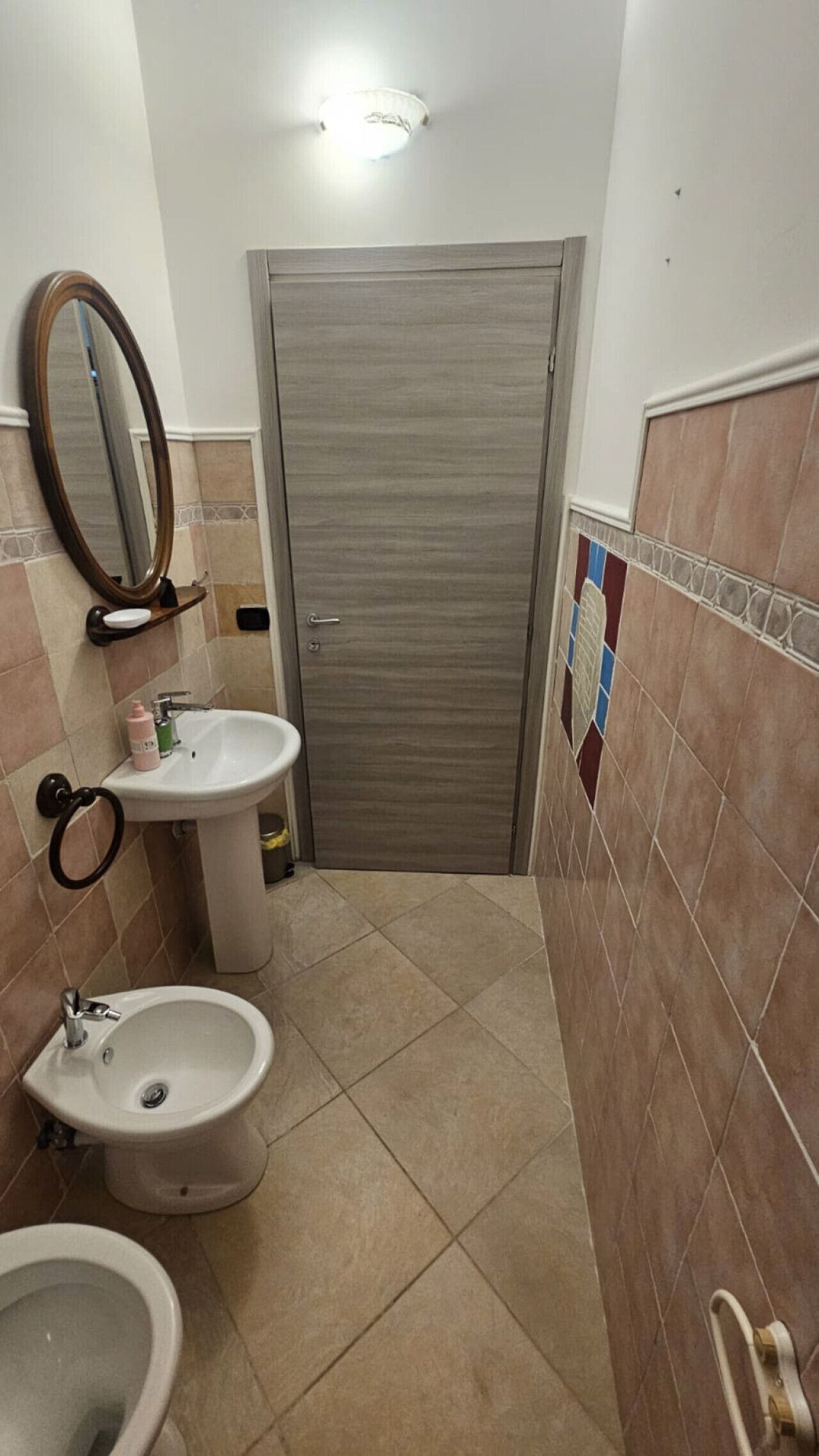 A small bathroom with a sink, bidet, and mirror.