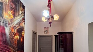 Un pasillo con una escalera, una puerta, un armario negro y una lámpara en el techo.