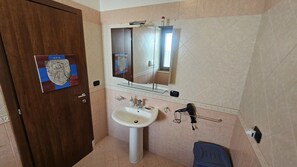 Un baño con lavamanos, espejo y secador de pelo.