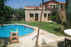 A pool with a stone house in the background.