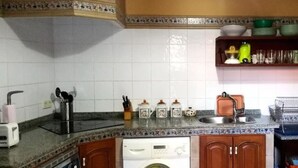 A kitchen with white tiled walls, a granite countertop, a built-in dishwasher, and wooden cabinets. - Tictágora House: House 1 (Plasenzuela)