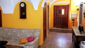 A living room with a sofa, a clock, and a wooden door. - Tictágora House: House 1 (Plasenzuela)