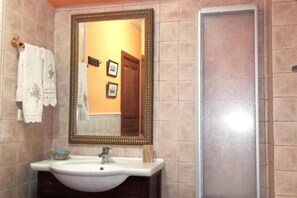 A bathroom with a large mirror, a sink, and a shower.