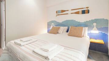 A hotel room with a bed, pillows, and a wall decoration of oars.
