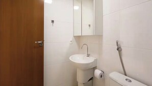 Ein Badezimmer mit Holztür, weißen Fliesen, einem Waschbecken, einem Spiegel und einer Dusche.