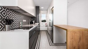 Een moderne keuken met een decoratieve spatwand, roestvrijstalen apparatuur en een houten tafel.