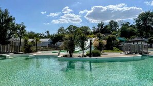 Una piscina cristalina con un deck circundante, palmeras y un pabellón.