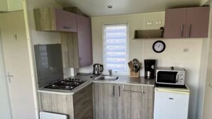 Una cocina compacta con estufa a gas, pileta y microondas.
