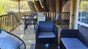 Un espacio de estar techado al aire libre con mobiliario de mimbre y una terraza de madera.