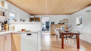 Une cuisine moderne avec un plafond en bois, des meubles blancs et un îlot central.