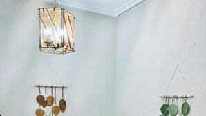 A dining area with a wooden table, white chairs, a hanging light fixture, and wall decorations. - Casona Mayor (pets allowed) (Andorra)