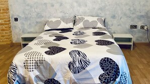 A bed with a patterned bedspread, a brick wall, and a wooden floor. - Casona Mayor (pets allowed) (Andorra)