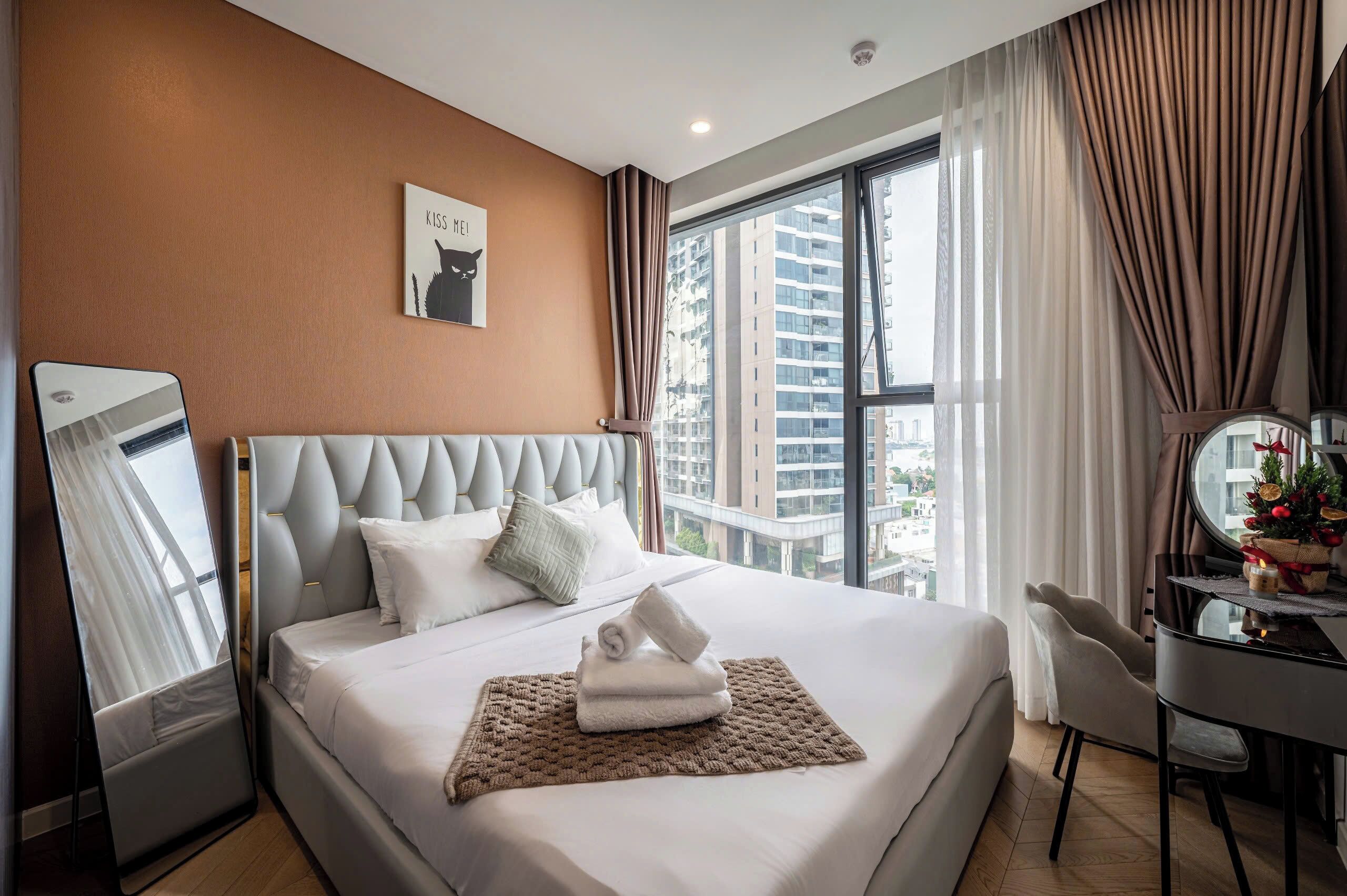 Ein Hotelzimmer mit einem großen Bett, einem Schreibtisch mit Spiegel und Blick auf die Stadt durch das Fenster.
