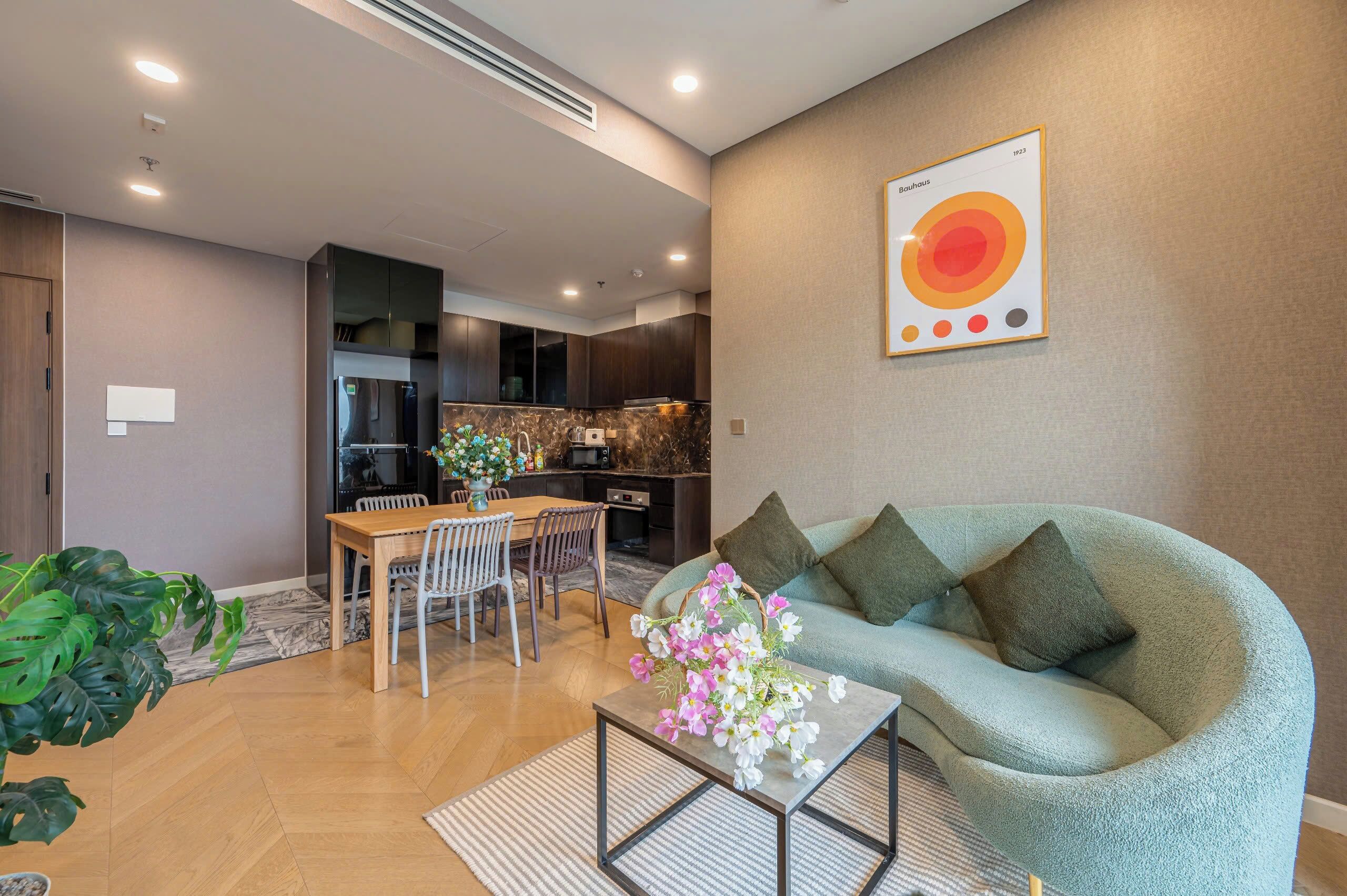 Una sala de estar moderna con un sofá, una mesa de comedor con sillas y una cocina al fondo.