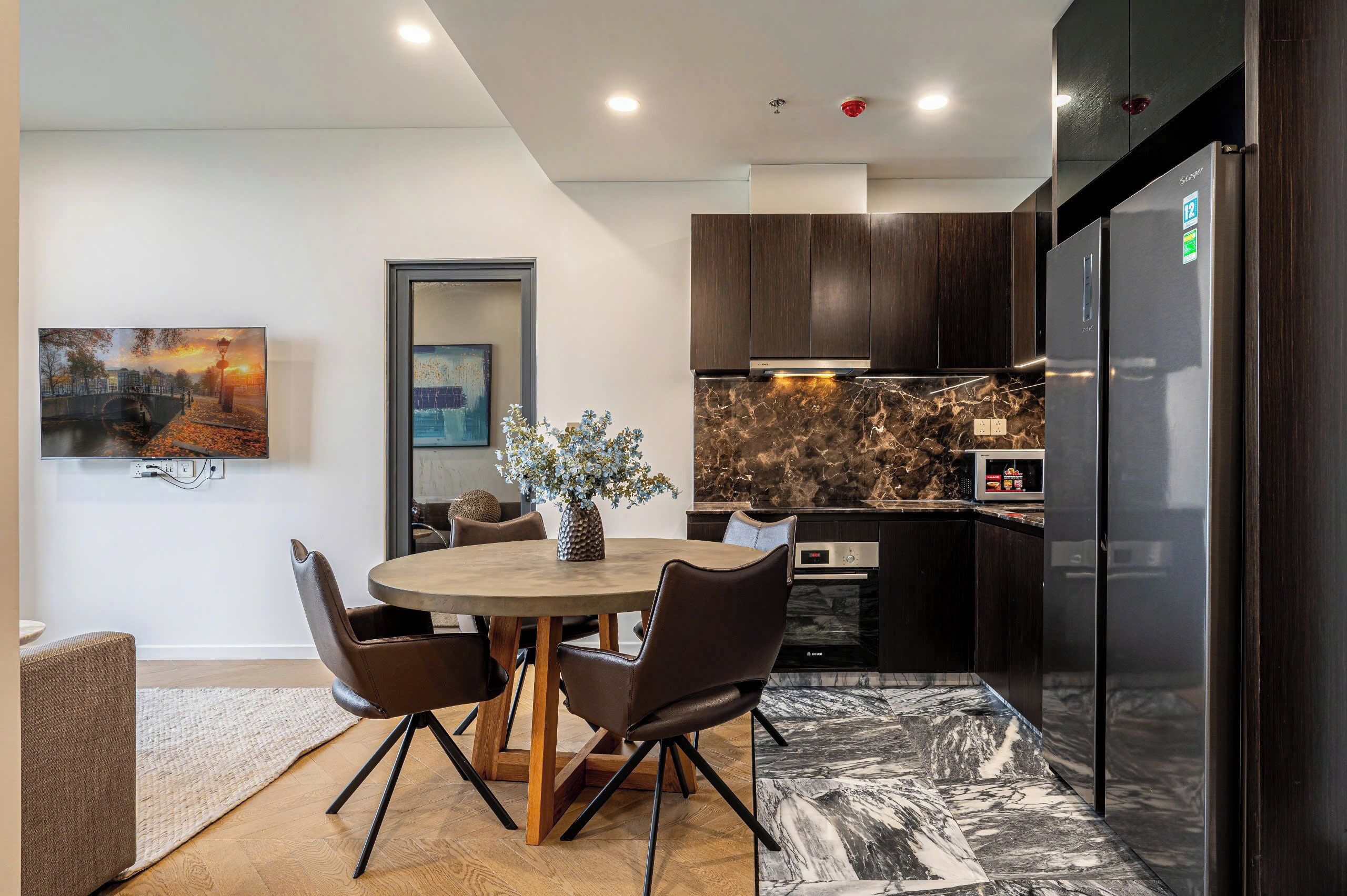 A modern kitchen with dark wood cabinets, a marble countertop, and a built-in oven.
