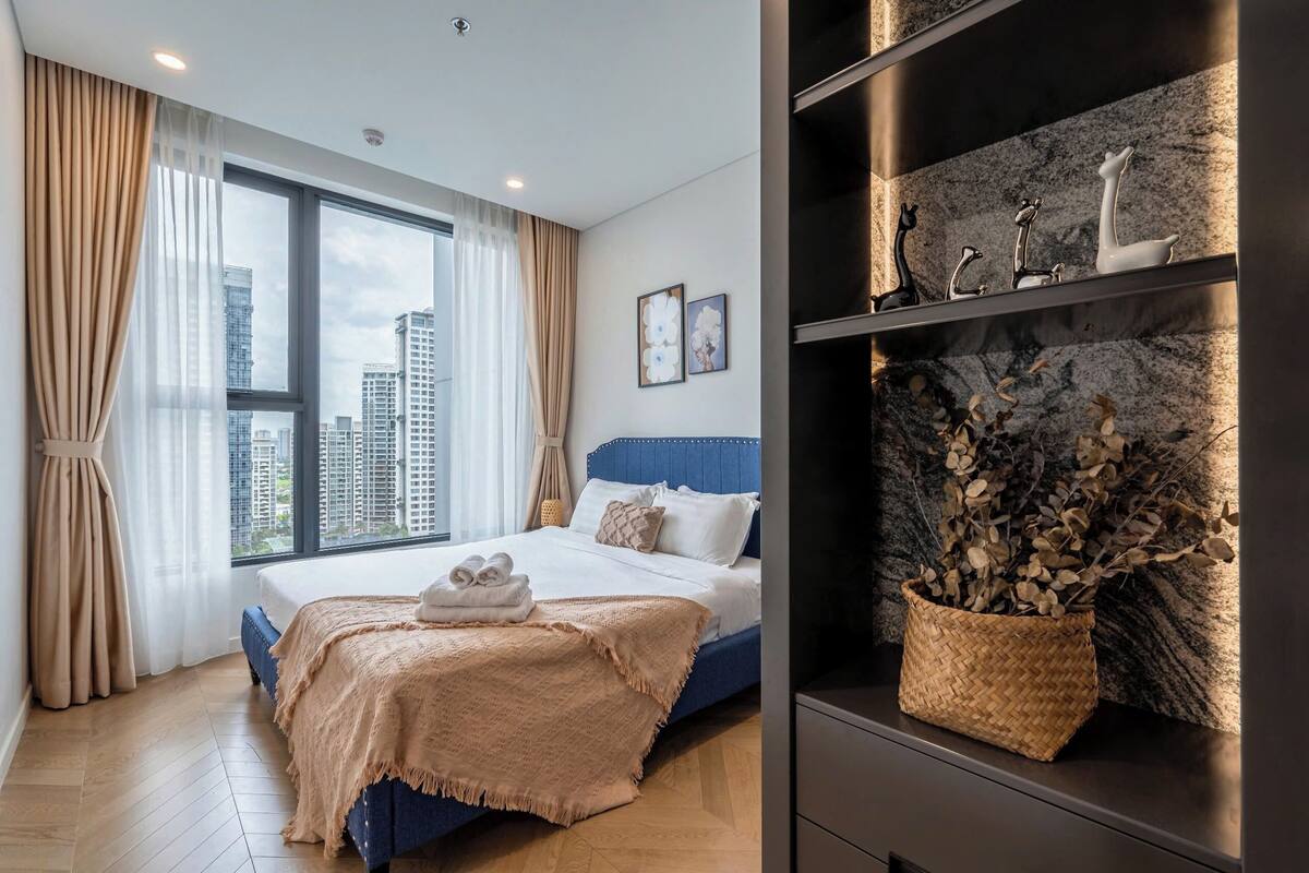 Quarto moderno com uma cama grande, vista para a cidade e estantes decorativas.