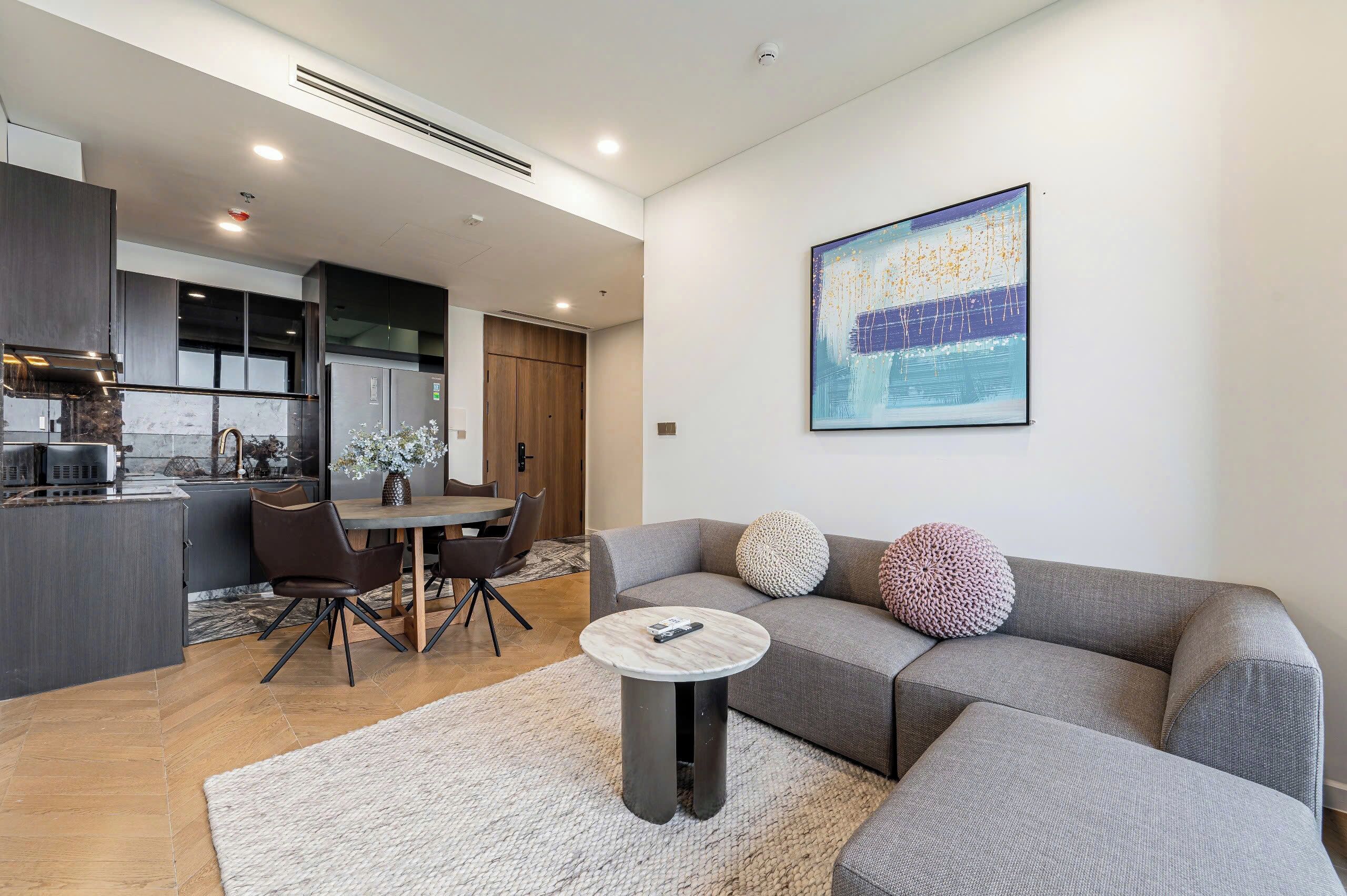 A modern living room with a grey sofa, round coffee table, and a dining area with a table and chairs.