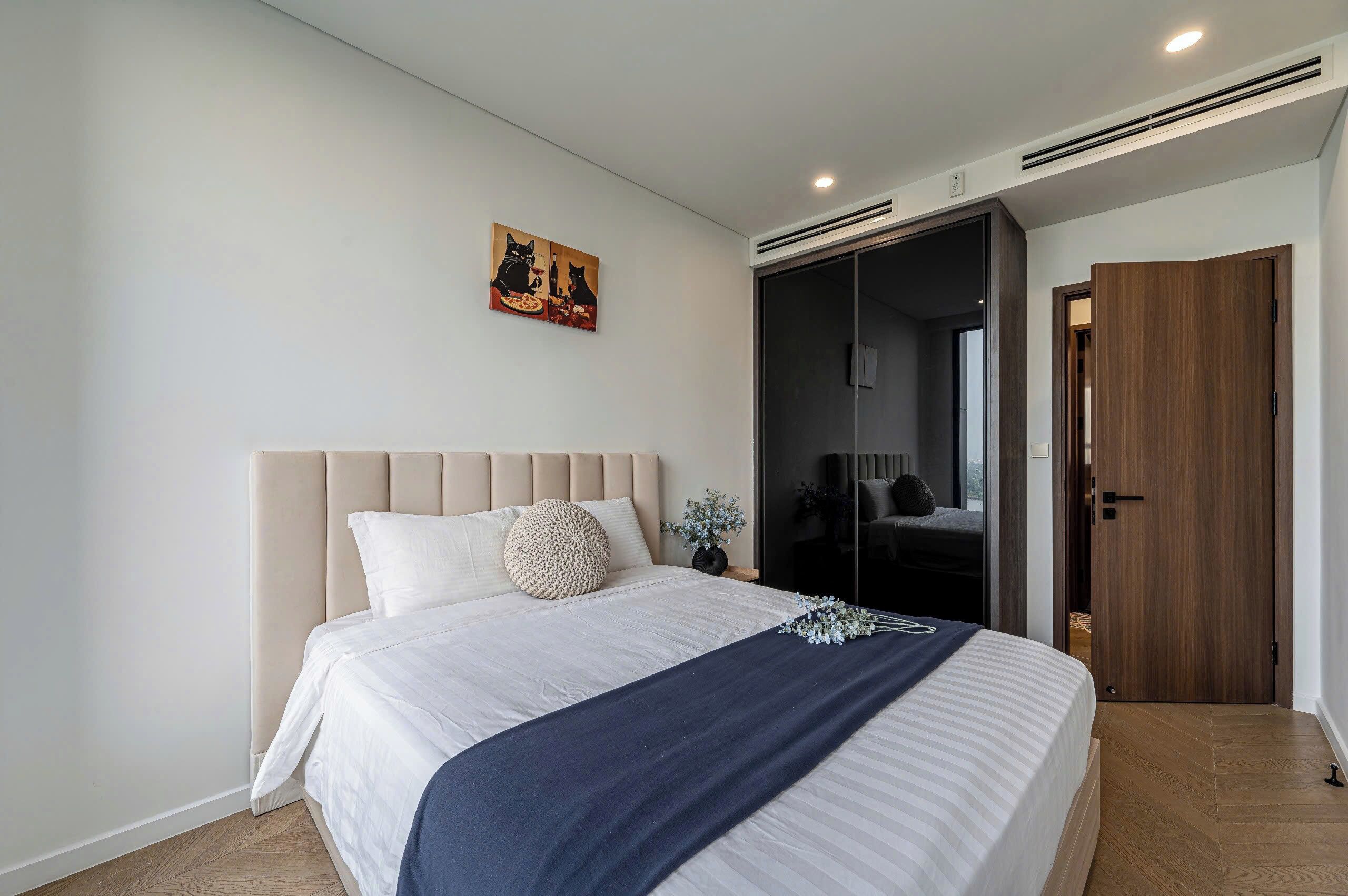 A modern bedroom with a large bed, a dark wooden wardrobe, and a sliding door closet.