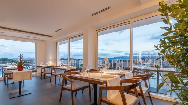 A modern dining area with large windows, wooden tables, and chairs. - Modern, tastefully furnished hotel room of approximately 28 square meters, featuring a double bed and a single bed, a bathroom with a bathtub or shower, and a large balcony furnished with a table and chairs.Use of the pool and gymUnlimited access to the  (Olbia)