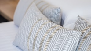 A bed with multiple pillows featuring a geometric pattern. - Modern, tastefully furnished hotel room of approximately 28 square meters, featuring a double bed and a single bed, a bathroom with a bathtub or shower, and a large balcony furnished with a table and chairs.Use of the pool and gymUnlimited access to the  (Olbia)