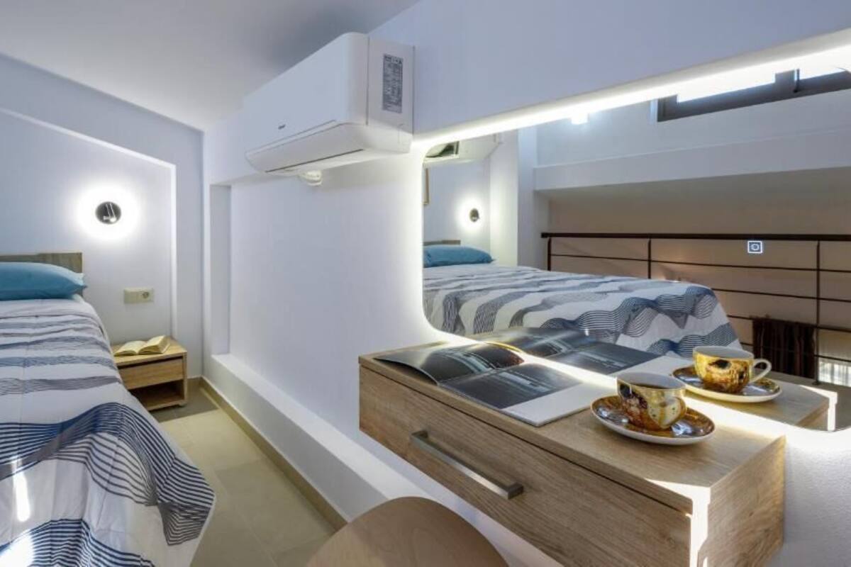 A modern hotel room with two beds, a large mirror, bedside tables, and a wooden dresser.