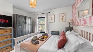 Ein Schlafzimmer mit Bett, Fernseher, Kleiderschrank, Fenster und Nachttisch.