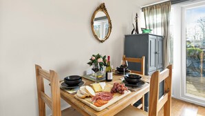 Ein Esstisch mit einer Auswahl an Käse, Fleisch und Trauben, dazu Weingläser und ein Spiegel an der Wand.