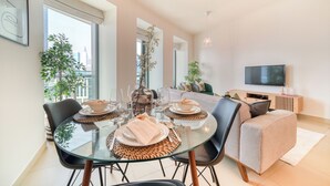 A modern dining area with a glass table, black chairs, and a sofa in the background. - Burj Vista 1- Mint Stay (Dubai)