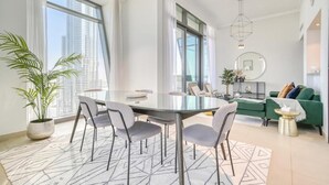 A modern living room with a dining area, large windows, and a green sofa. - Burj Vista 1- Mint Stay (Dubai)