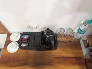 A wooden table with a kettle, a water bottle, and two cups with lids. - Stayvilla Prime (Ranchi)