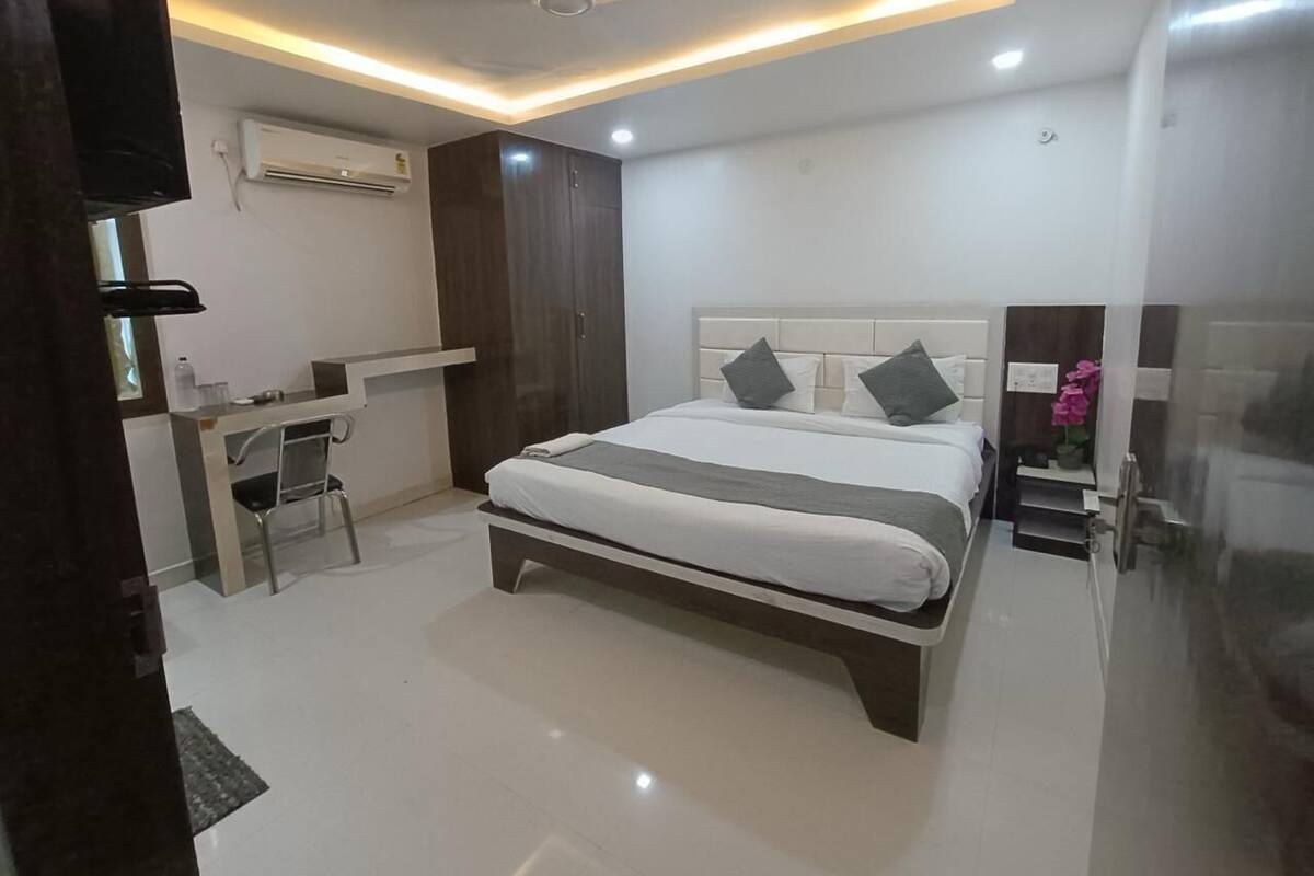 Um quarto moderno com uma cama, mesas de cabeceira, uma escrivaninha e um aparelho de ar condicionado.