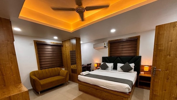 Une chambre moderne avec un grand lit, un canapé, des éléments décoratifs en bois et un ventilateur de plafond.