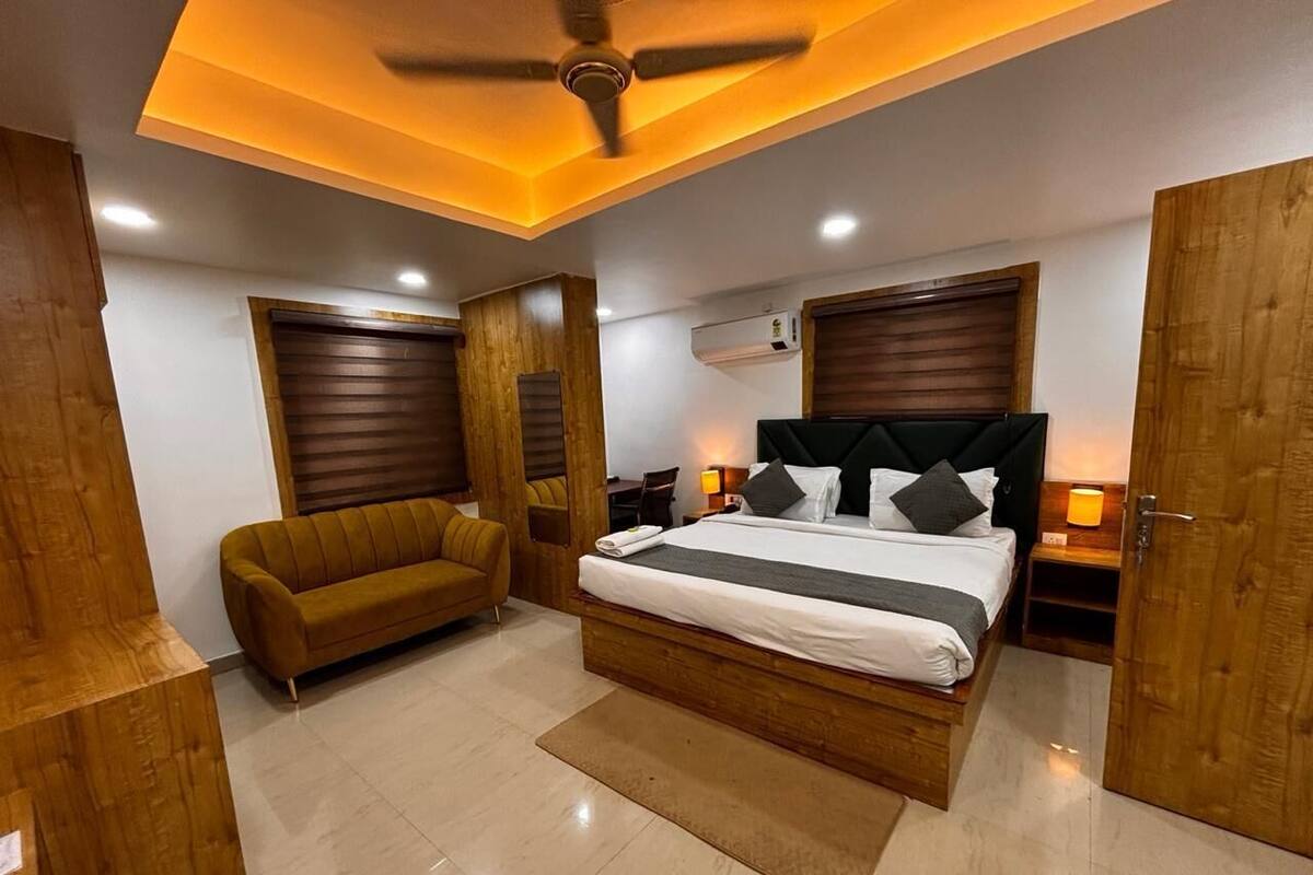 Um quarto moderno com uma cama grande, um sofá, detalhes em madeira e um ventilador de teto.