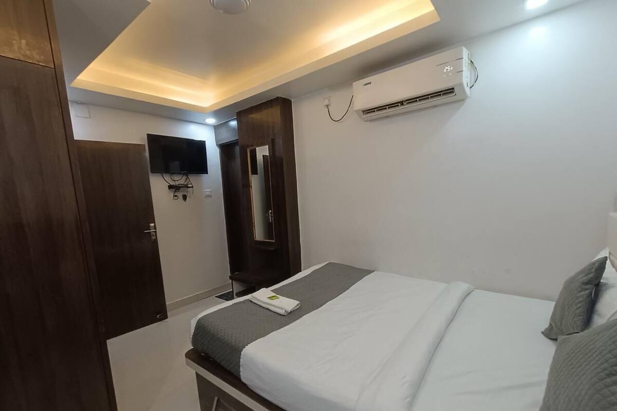 Quarto de hotel com cama, guarda-roupa, ar condicionado e televisão.
